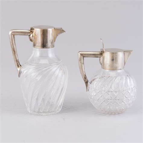 Two glass carafes with hinged silver lids and silver handles, K ...