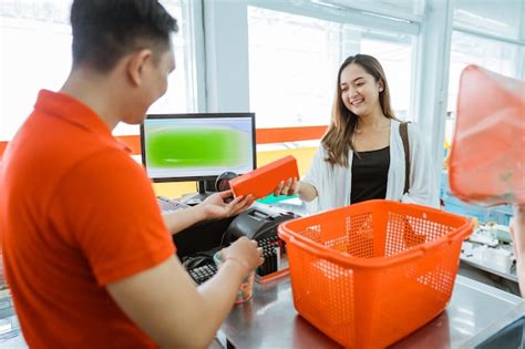 Male store clerk hands items to a female customer while removing them ...