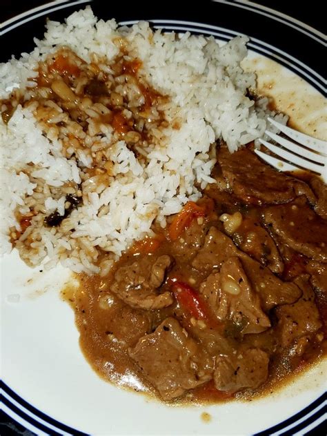 A bowl of slow cooker pepper steak, served over white rice