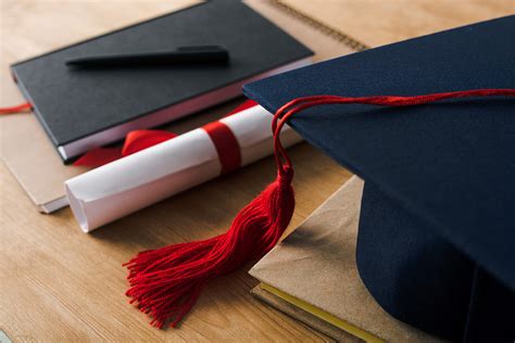 桌子上的博士帽和毕业证带有木制背景的钢笔、文凭和毕业帽的笔记本的选择性焦点图片下载 - 觅知网