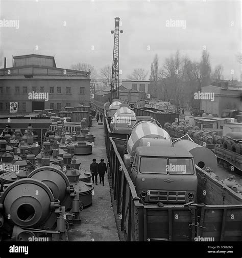 Newly manufactured concrete mixer trucks are loaded onto open railway cars for shipment, while ... - distribution of output in planned economy