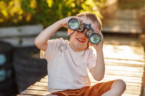 小男孩在河岸码头上看着双筒望远镜坐在高清图片下载-正版图片502517847-摄图网