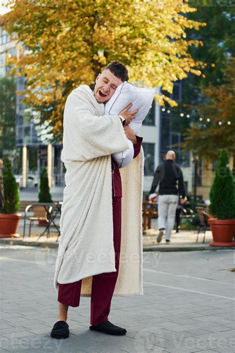 Young man in pajama is outdoors on the street. Feels sleepy 15304730 ...