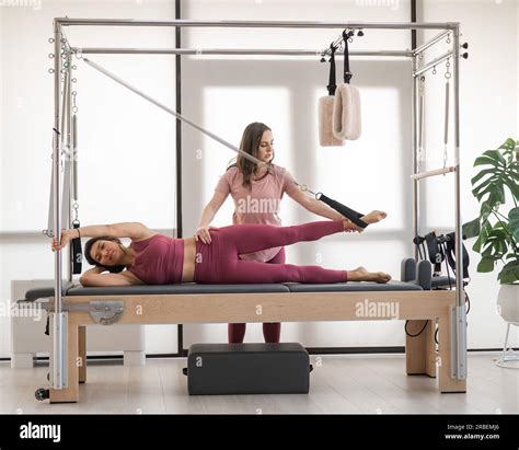 Asian woman doing pilates with trainer on cadillac reformer Stock Photo ...