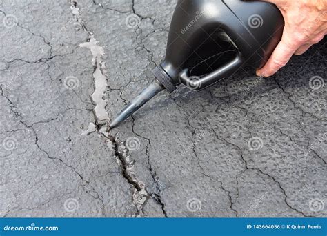 Repairing Cracks in Driveway with Asphalt Crack Filler Stock Photo ...