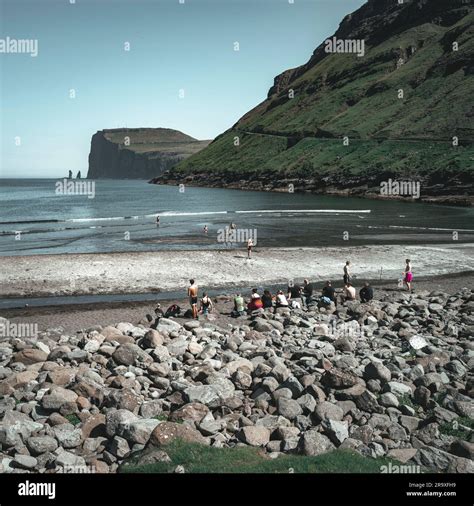A group of people on the beach shore of the Faroe Islands against a ...