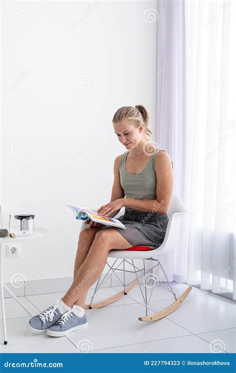 Young Woman Sitting at the Chair at Home Reading a Magazine Stock Image ...