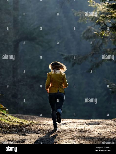 Woman makes a light jog in the misty forest in the morning, dawn and ...