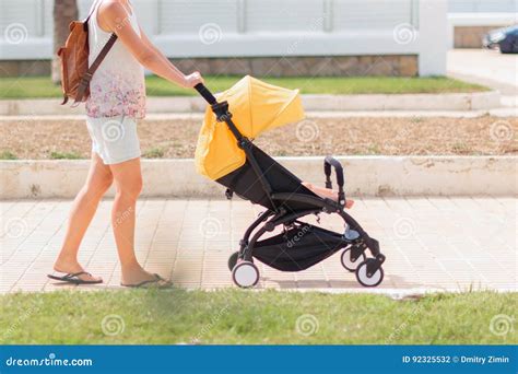 Young Mom Pushing Stroller with Sleeping Baby by the Street Stock Photo ...