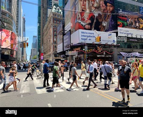 A crowd of people cross the street in the heart of New York City Times ...