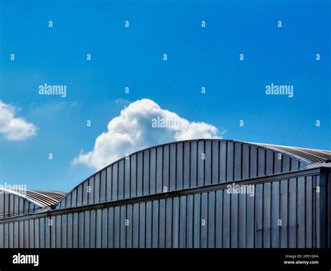 arched corrugated aluminum clad hangar building roof detail. blue sky ...