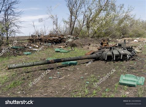A man walks past a burnt armoured personnel carrier near buildings destroyed in the course of Ukrain