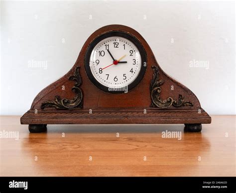 Old-fashioned, decorative desk clock. Old clock against a white wall ...