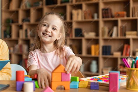 Niña feliz jugando con coloridos bloques de madera y sonriendo a la ...