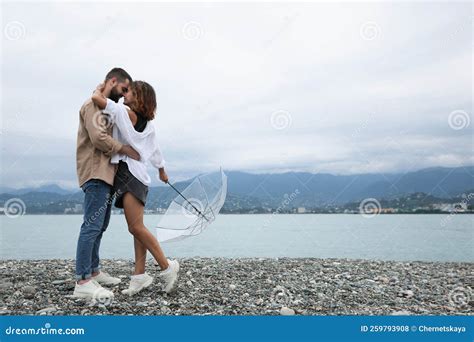 Young Couple with Umbrella Enjoying Time Together Under Rain on Beach ...