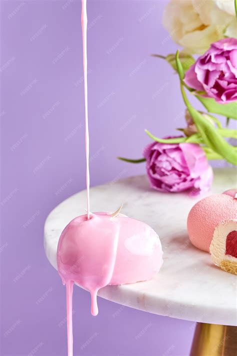 Premium Photo | A mousse cake is poured with icing on a pink background ...