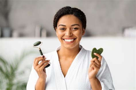 Beauty tools smiling black woman holding jade guasha scraper and ...
