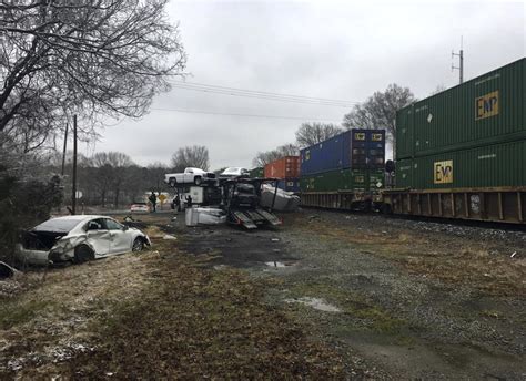 Train hits car carrier; 2 crew members hurt, highway closed | AP News