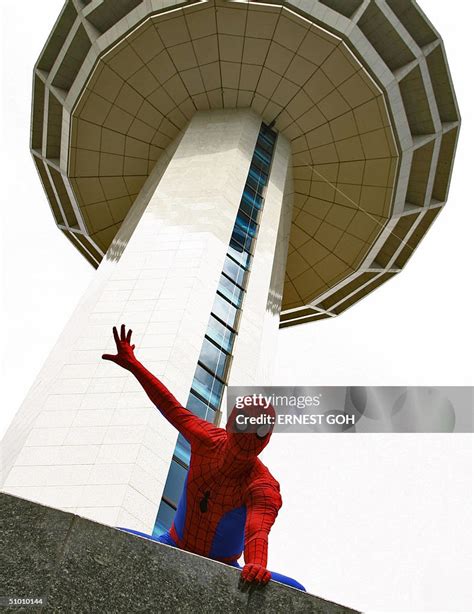 Comic superhero, 'Spiderman' gestures as he scales the 80-metre high ...