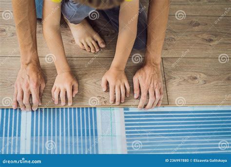 Father and Son Installing New Wooden Laminate Flooring on a Warm Film ...