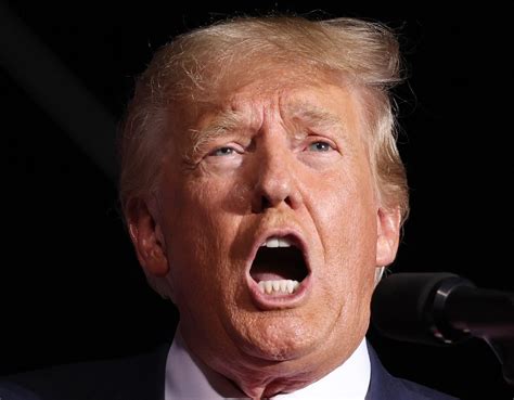 A banner showing an image of President Donald Trump is seen behind an American flag outside a US Dep Minimalist