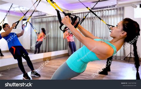 Fitness asian people exercising with trx straps in gym. group of friends doing workout together ...