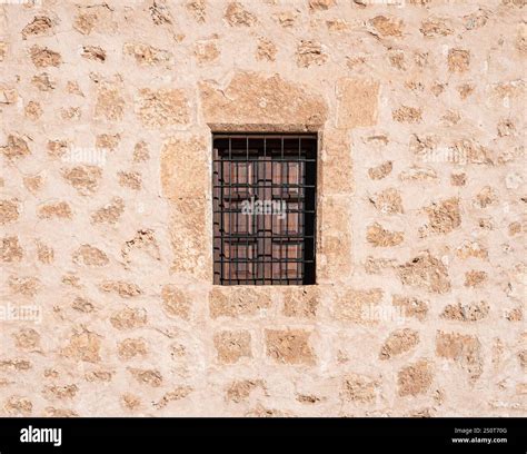 Ancient Spanish stone wall with a metal iron grid window as a prison in ...