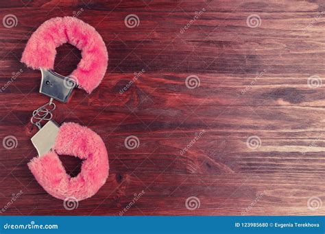 Fluffy Pink Handcuffs on a Dark Wooden Table Stock Photo - Image of ...