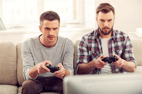 Focused on game. Two concentrated young men playing video games while ...