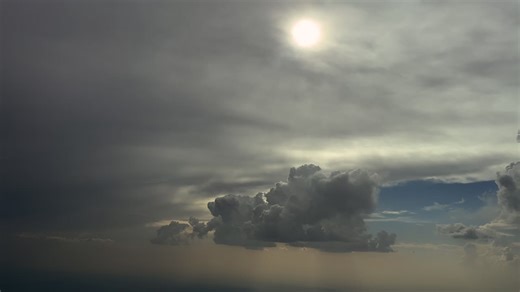 An immervive pilot’s view from inside a jet cockpit flying through a stormy sky with some threatening storm clouds and the sun veiled by a layer of ethereal clouds. 4K | Premium Stock Video Footage