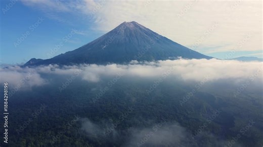 Stone river, stone deposit and Mount Semeru. Volcano clouds of smoke against the blue sky. Active volcano on the island of Java in Indonesia. Ash pillar from a bird's eye view. Dron. 4K