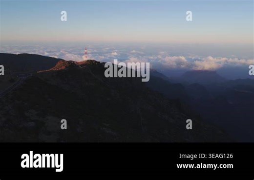 Stunning sunrise timelapse sequence over Madeira's mountainous landscape. Golden light illuminates a dramatic ridge with communication tower while clouds blanket the valley below, capturing the ser Stock Video Footage - Alamy