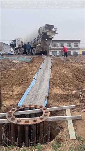 Concrete pouring for utility pole foundation using a chute.