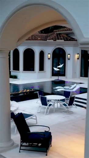 Modern pool in Jupiter, Florida with an infinity edge, Ledge Loungers, in pool fire feature, custom sculpture, and a knife edge. A knife edge pool has water that sits at the same level as the pool deck to create a mirror surface effect. #insanepools #lucaslagoons #modern | Lucas Lagoons Design