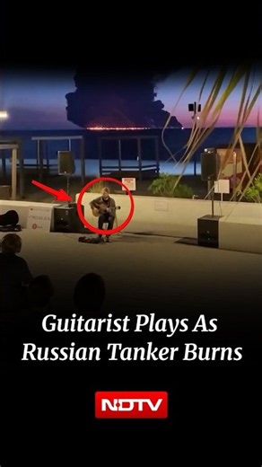 Russian Man Plays Guitar As Drone Hit Oil Tanker Burns In The Background