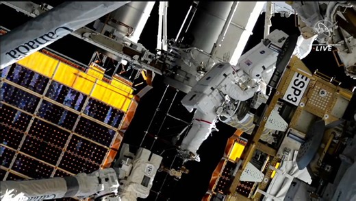 Spacewalkers installing roll out solar array at space station