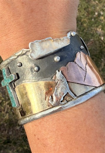 “Desert under the moon” 7 stars in the sky to symbolize all of Gods perfect creation. A wide Tufa casted Sterling silver band. Brass and copper landscape overlay. Sterling coyote howling at the moon and a copper desert hare. Crushed turquoise inlay and plume agate cloud. And a full moon in sterling. I love pieces that tell a story… All of my pieces reflect the beauty of our creator. When something comes together like this it makes my heart leap with joy. Should I keep it? It’s my first ever Tufa