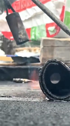 heating a black roll manually using an orange fire torch for a very neat building finishing work