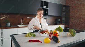 Young woman cooking, dancing at kitchen. Female cook food listen to music with headphones and dancing in the kitchen. Girl with vegetables play radio and dance, while cooking salad have fun at home.