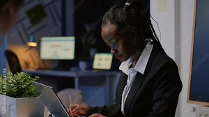 African american businesswoman writing company statistics on notebook while multi ethnic teamwork discussing management presentation in office meeting room. Diverse businesspeople brainstorming ideas