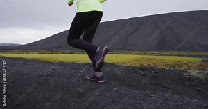 Sport fitness running woman trail runner on amazing nature path. Running shoes and legs closeup Healthy lifestyle girl training in beautiful nature, Iceland. Fit female runner. RED EPIC SLOW MOTION