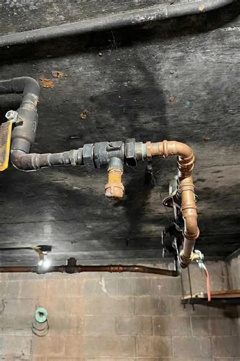 2.9K views | The image shows a plumbing system with copper pipes and fittings attached to a black ceiling. The pipes are connected to a valve, which appears to be controlling the flow of water or another fluid. The surrounding area is a basement or utility room, with a concrete block wall visible below the pipes. The overall atmosphere suggests a functional, industrial setting. | Only Plumbing | Facebook