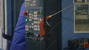 Side cropped shot of unrecognizable factory worker putting industrial air blow gun back to handle of controller panel during workday in manufacturing plant
