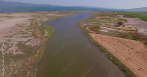 Aerial: A river delta with a road/bridge passing through and some agricultural buildings. Lesbos, Greece.