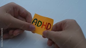 A child holding a yellow paper note in his hands with the abbreviation ADHD on it