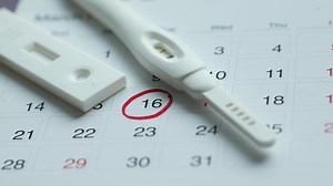 Pregnancy test kit on a calendar close up