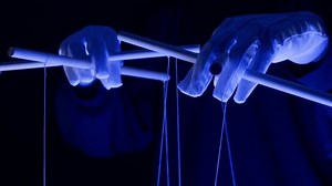 The puppeteer controls the puppets in the theater in blue neon light close-up. Managing people at work, in politics and government. Action control