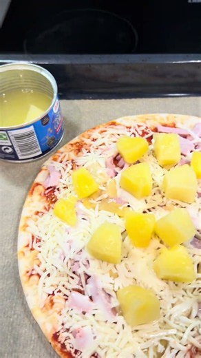 Adding extra pineapples to a Hawaiian pizza.
