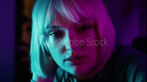 Serious young caucasian woman browsing mobile phone while a break during playing game at night on Desktop PC. Shot with RED helium camera in 8K.