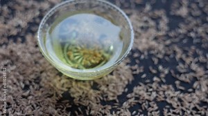 The Cinematic close-up shot of cumin seeds or zeera aka jeera (Cuminum cyminum) in a glass bowl along with its extracted water, Hd footage 24 FPS